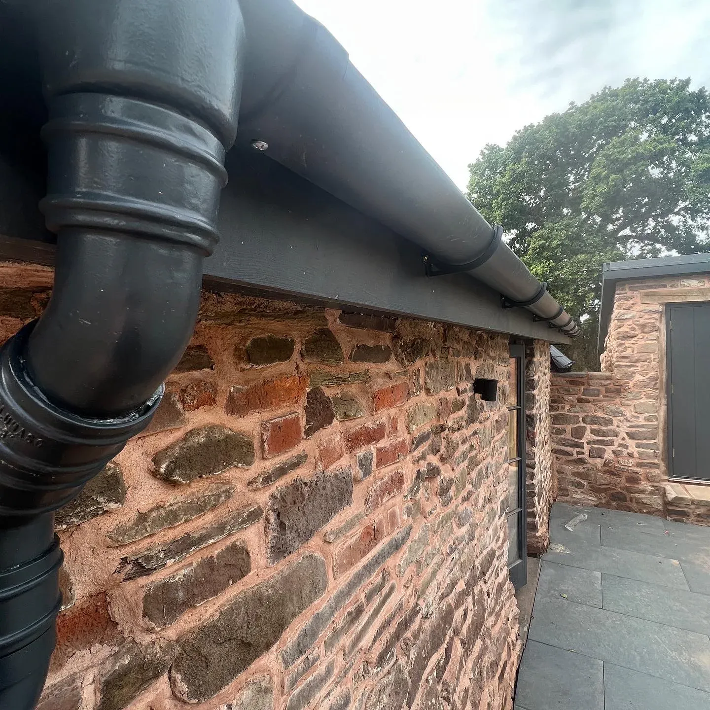 Cast iron downpipe on a lime-pointed stone wall