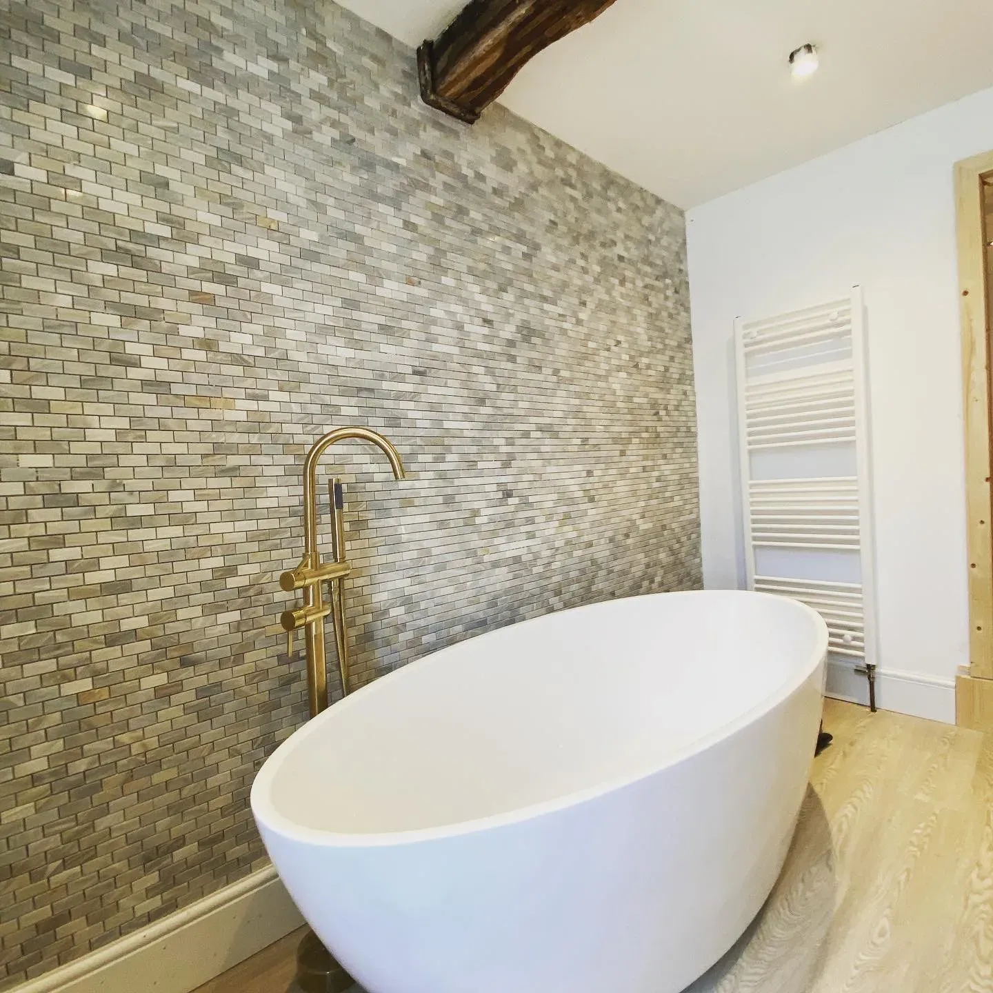Freestanding bath against a stone-tiled wall