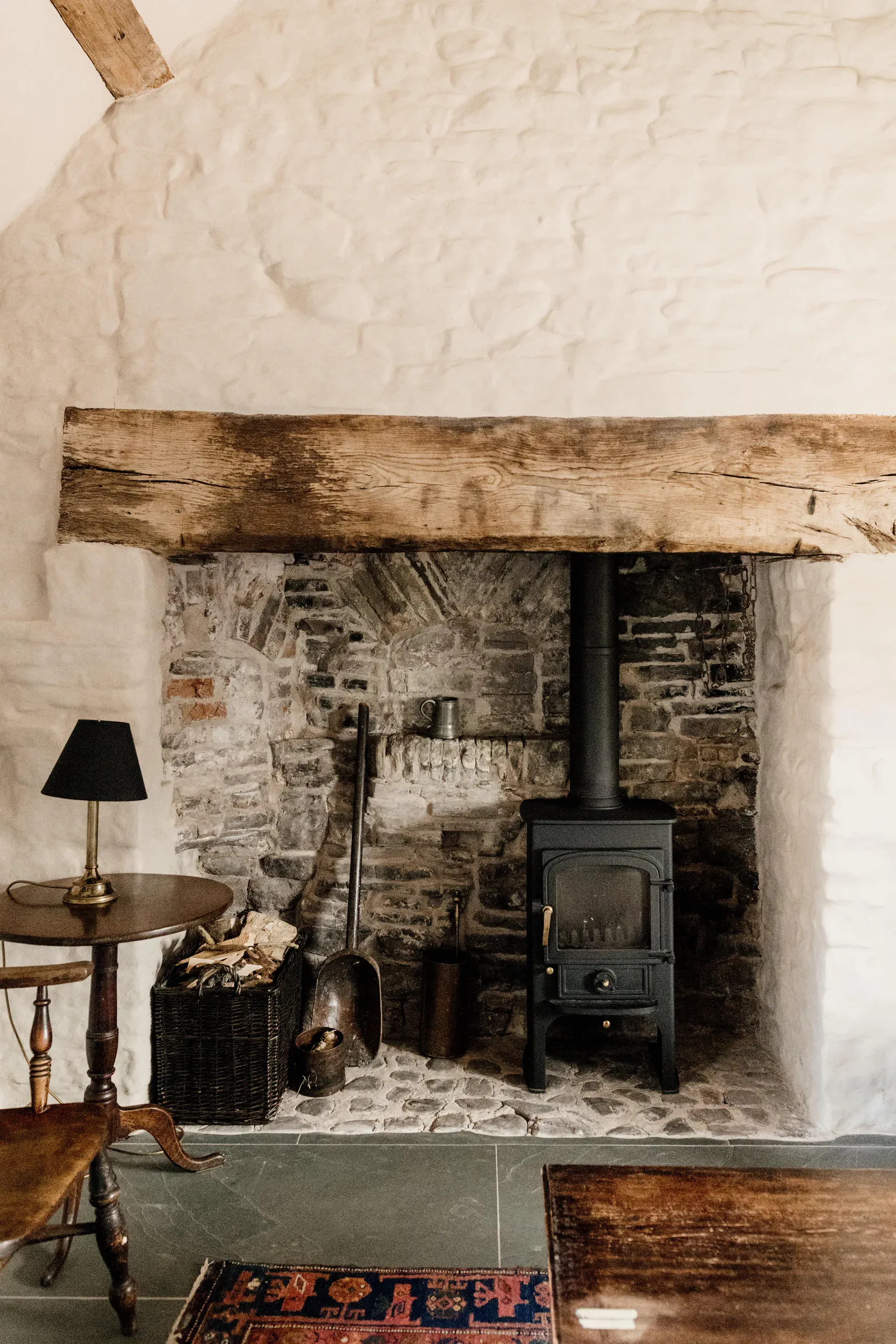 Inglenook fireplace with a wood-burning stove, exposed stone and a thick oak lintel