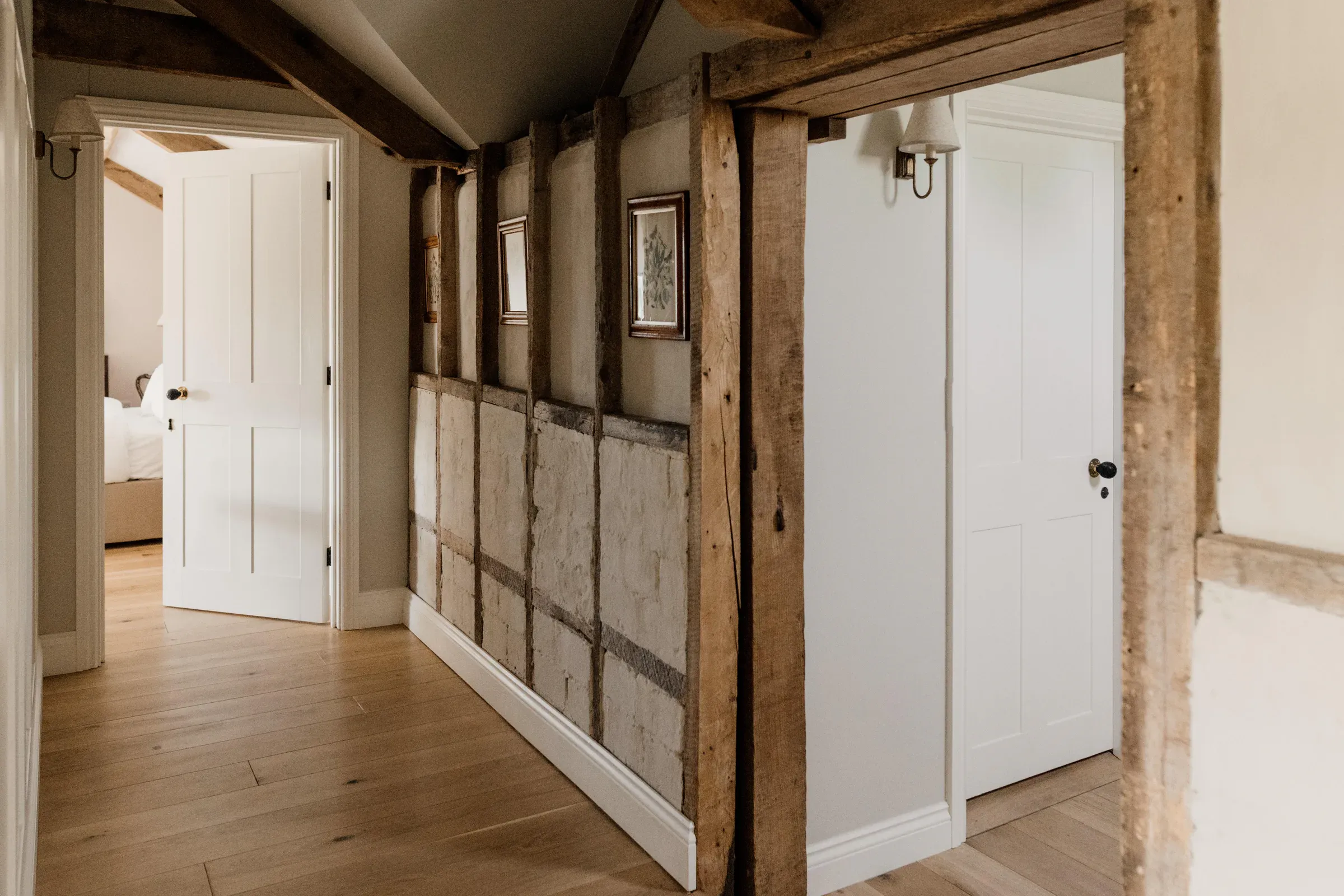 Hallway with a restored timber frame and lime-plastered panels, and an oak floor