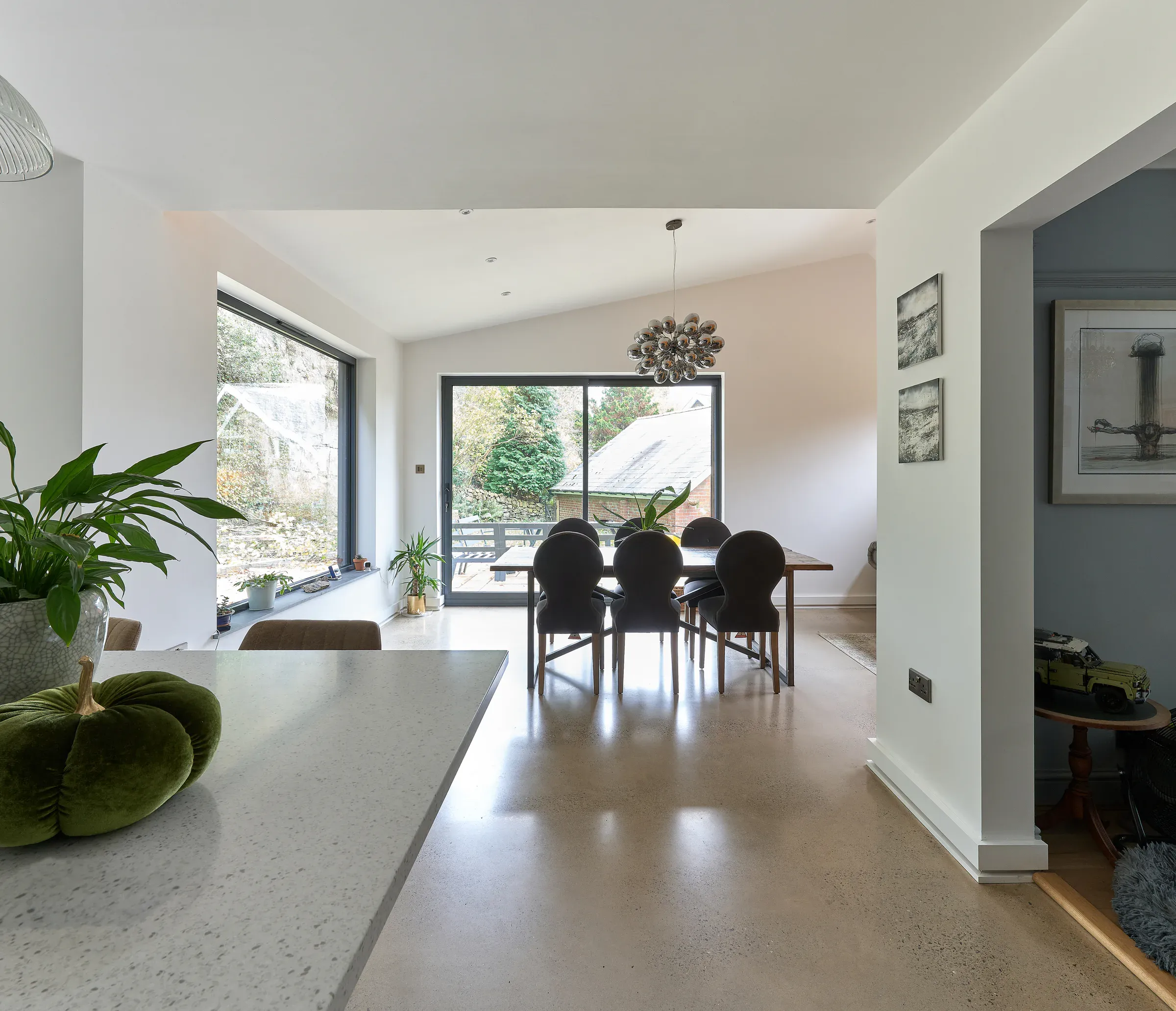 Open-plan living space with polished concrete floors and a vaulted ceiling, looking through to the dining area