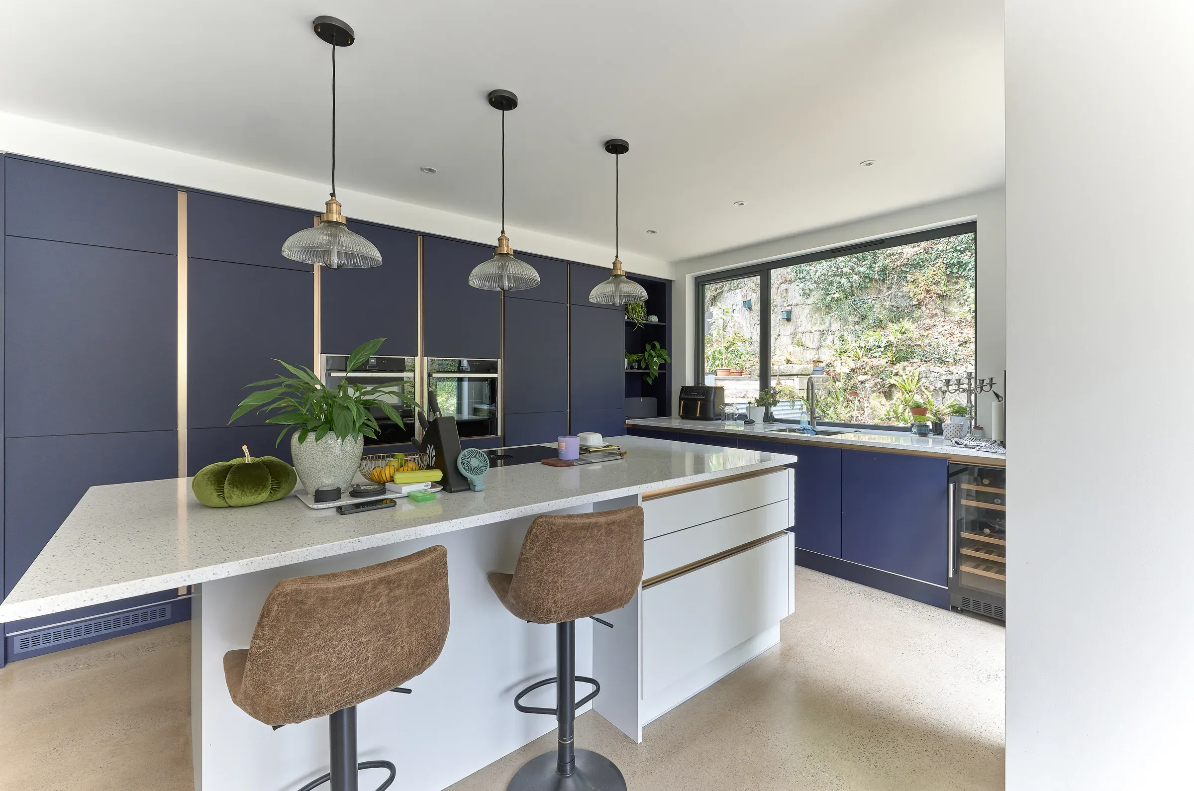 Kitchen island with pendant lights, looking out to the trees through the picture window