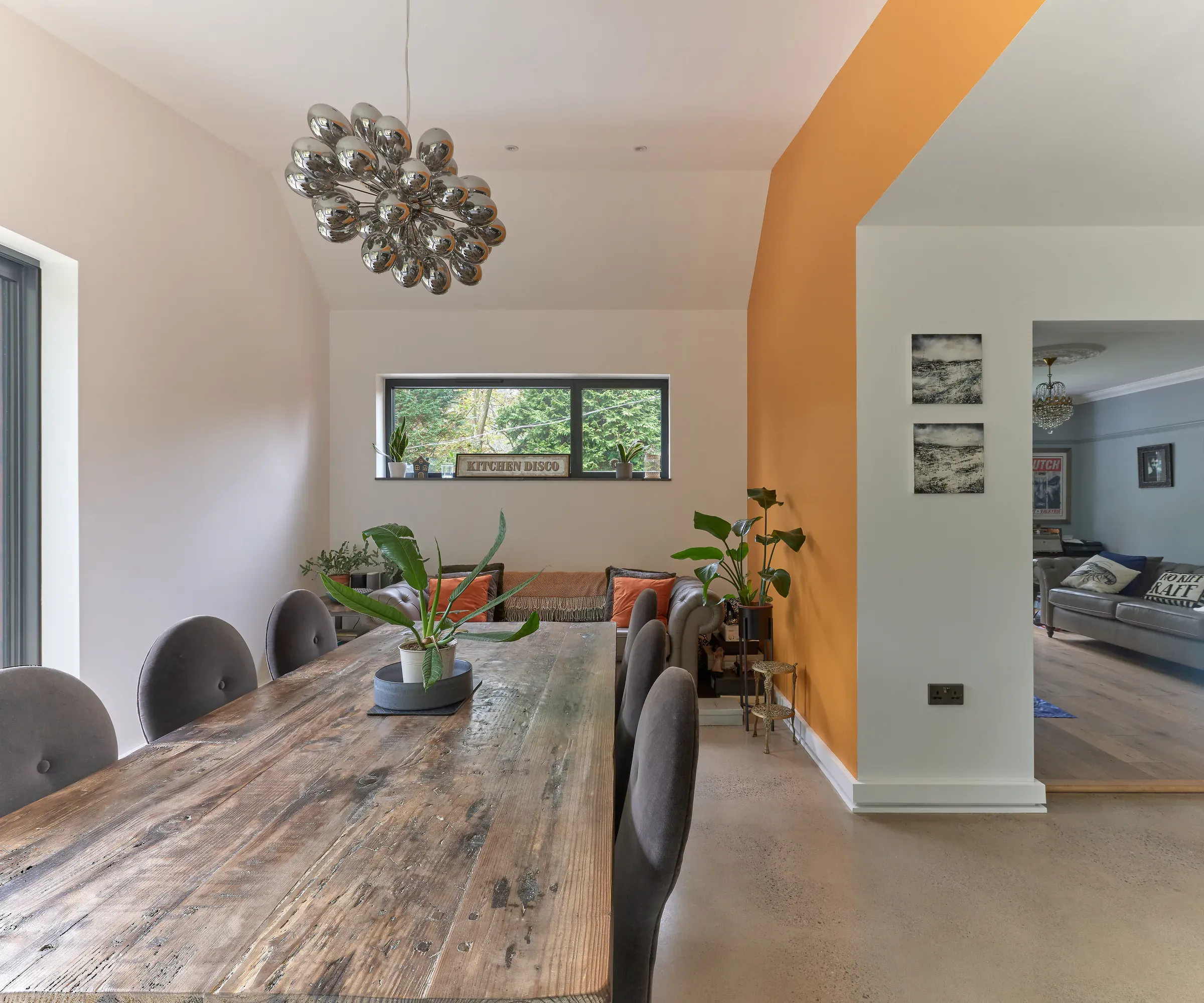 Dining area with the orange wall and a wide window framing the hillside