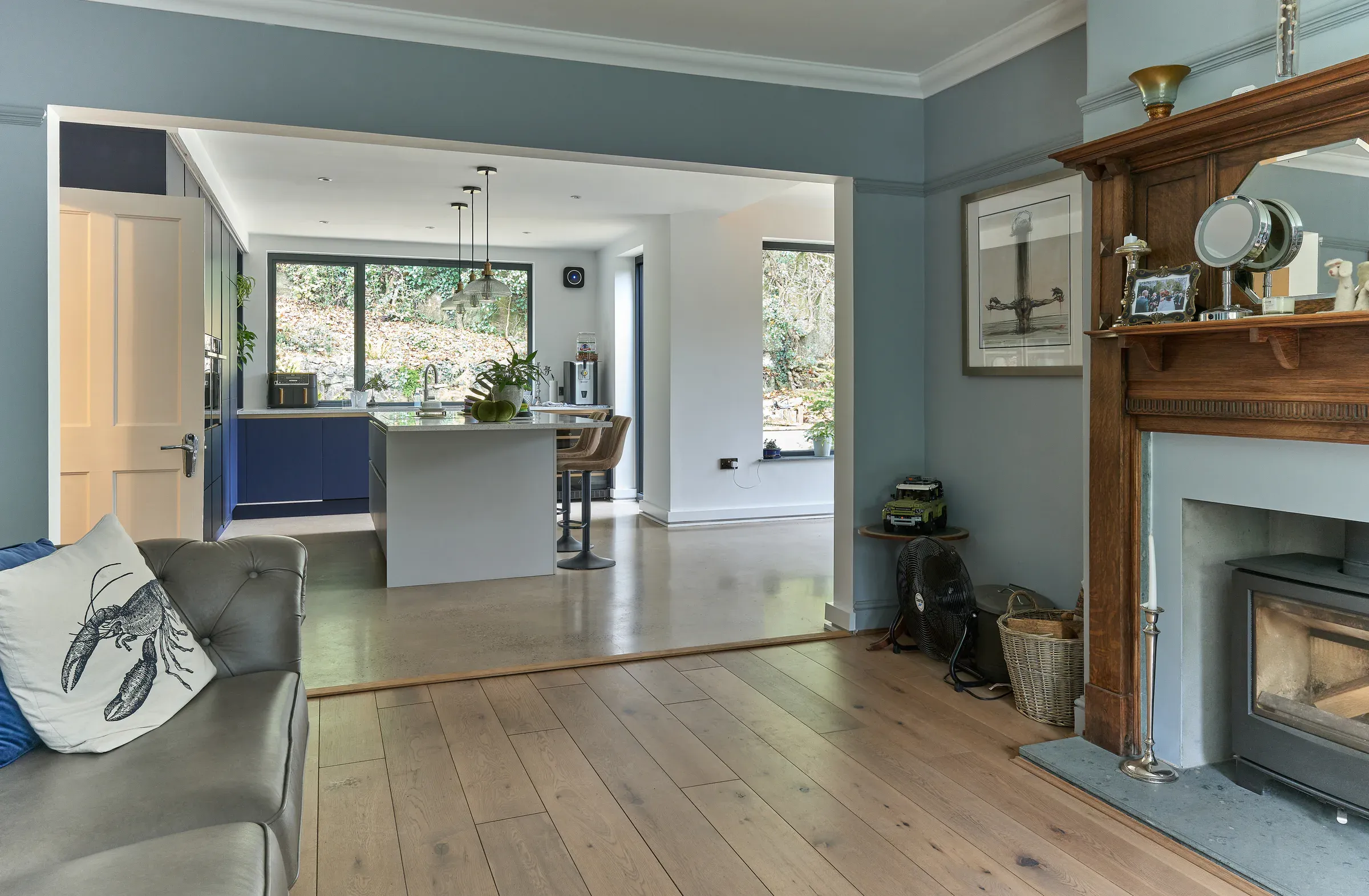 Sitting room with a cast iron fireplace, blue walls and the open-plan kitchen beyond