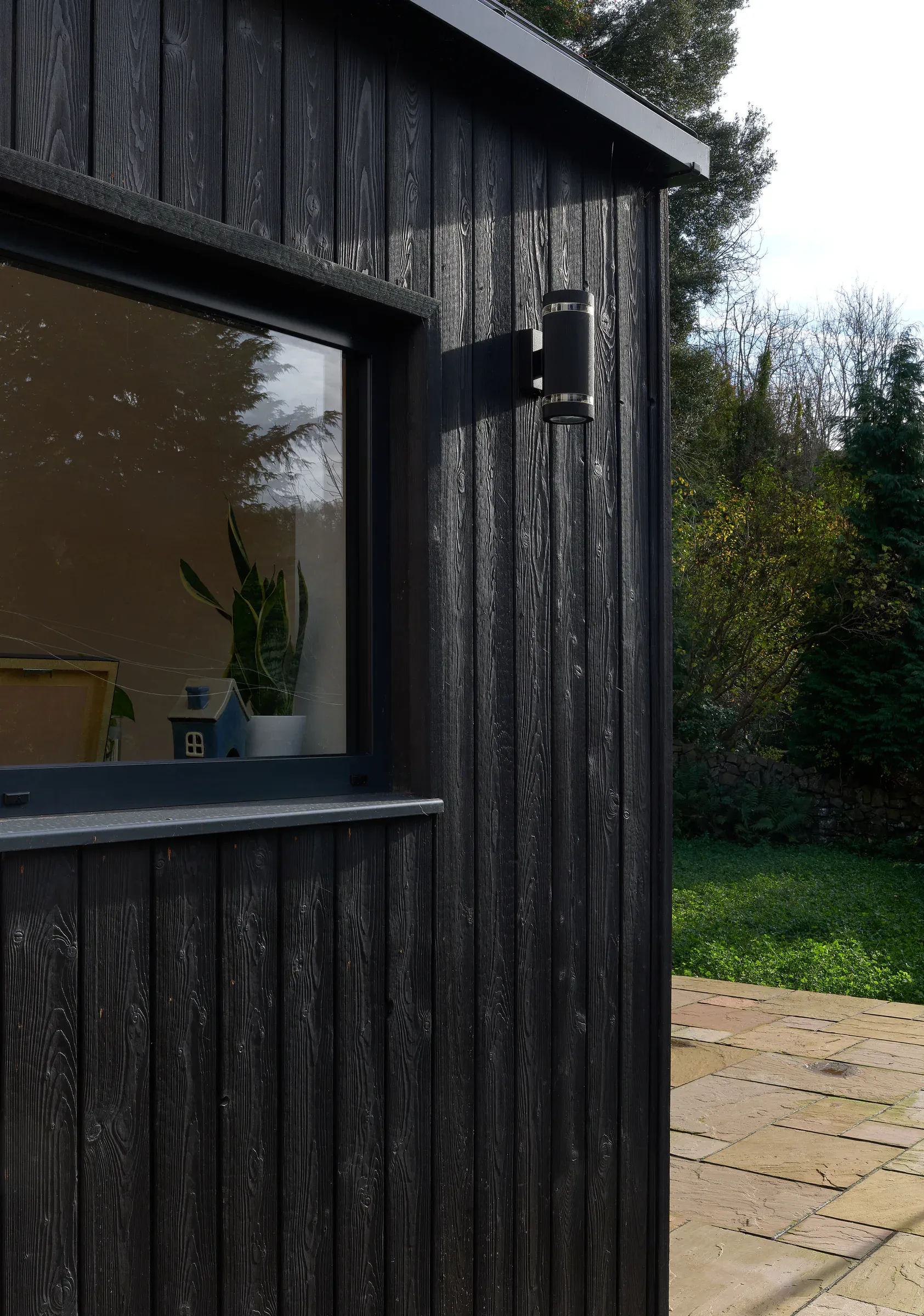 Detail of the burnt larch cladding and a dark-framed window