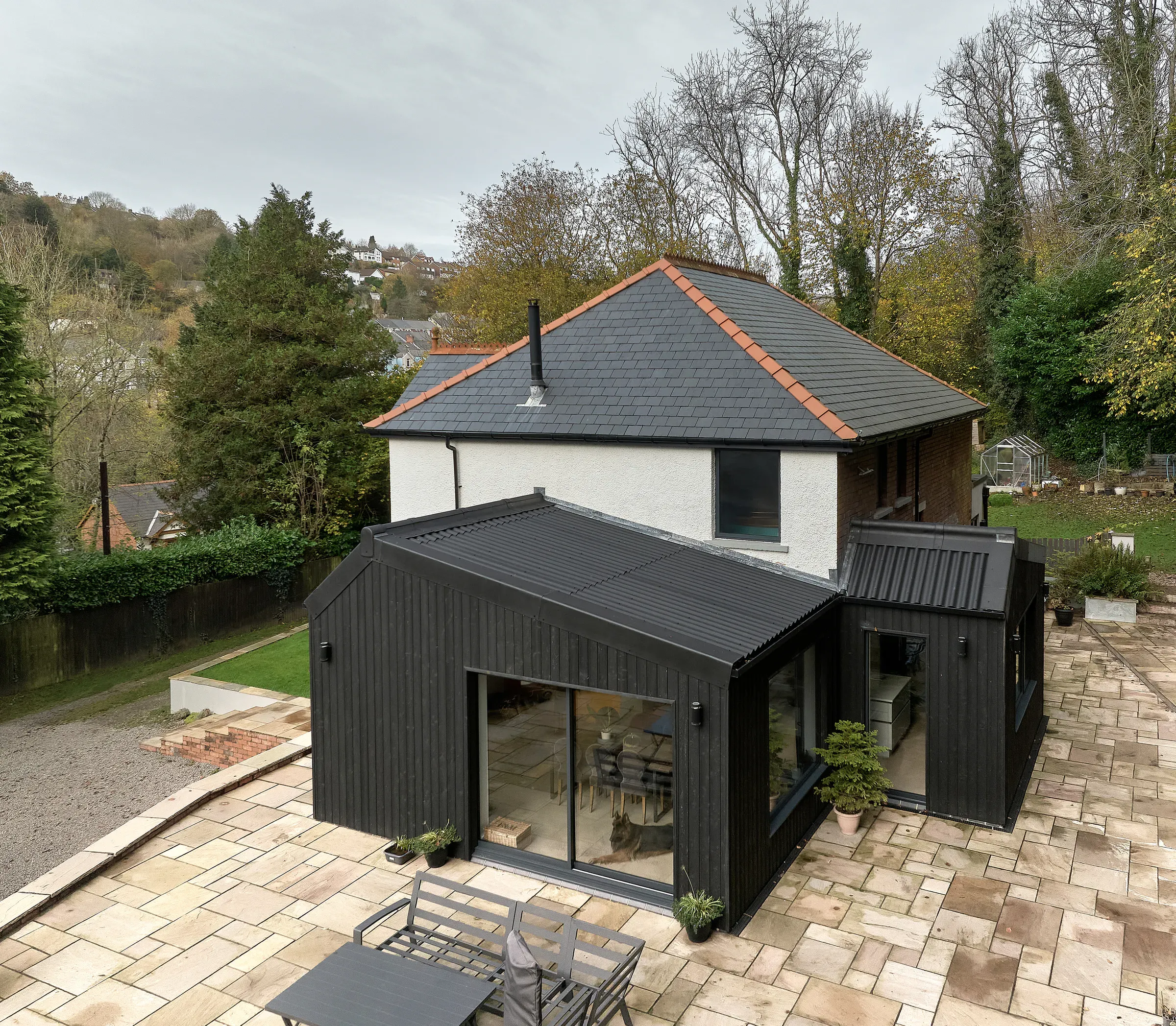 Drone view of the house from above the terrace, showing the three extensions and the slate roofs