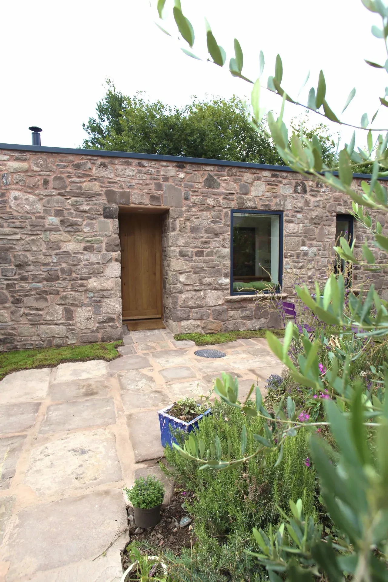 Stone façade of the garden room seen through the garden