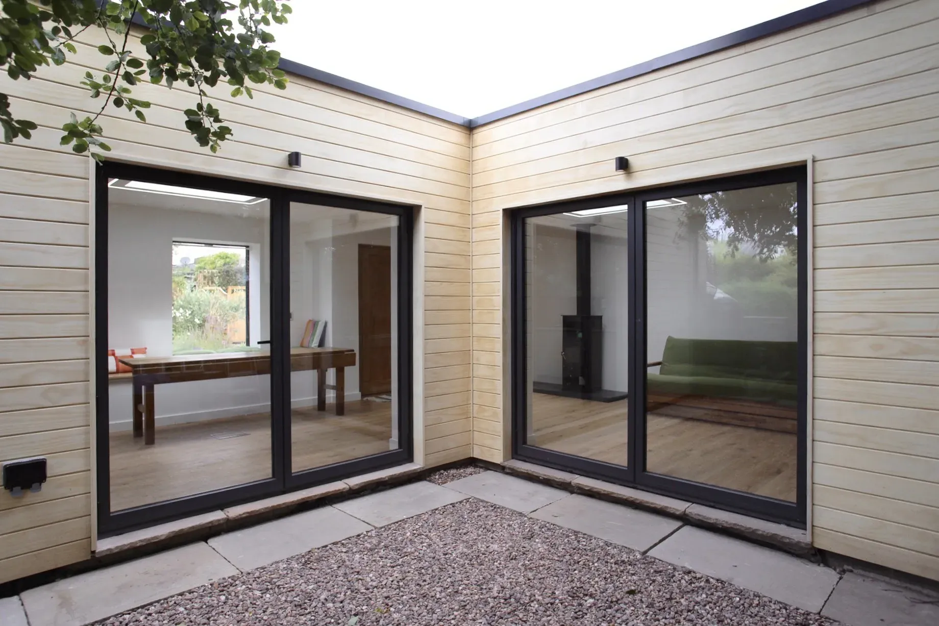 Rear elevation in Accoya cladding, with sliding glass doors onto a gravel courtyard
