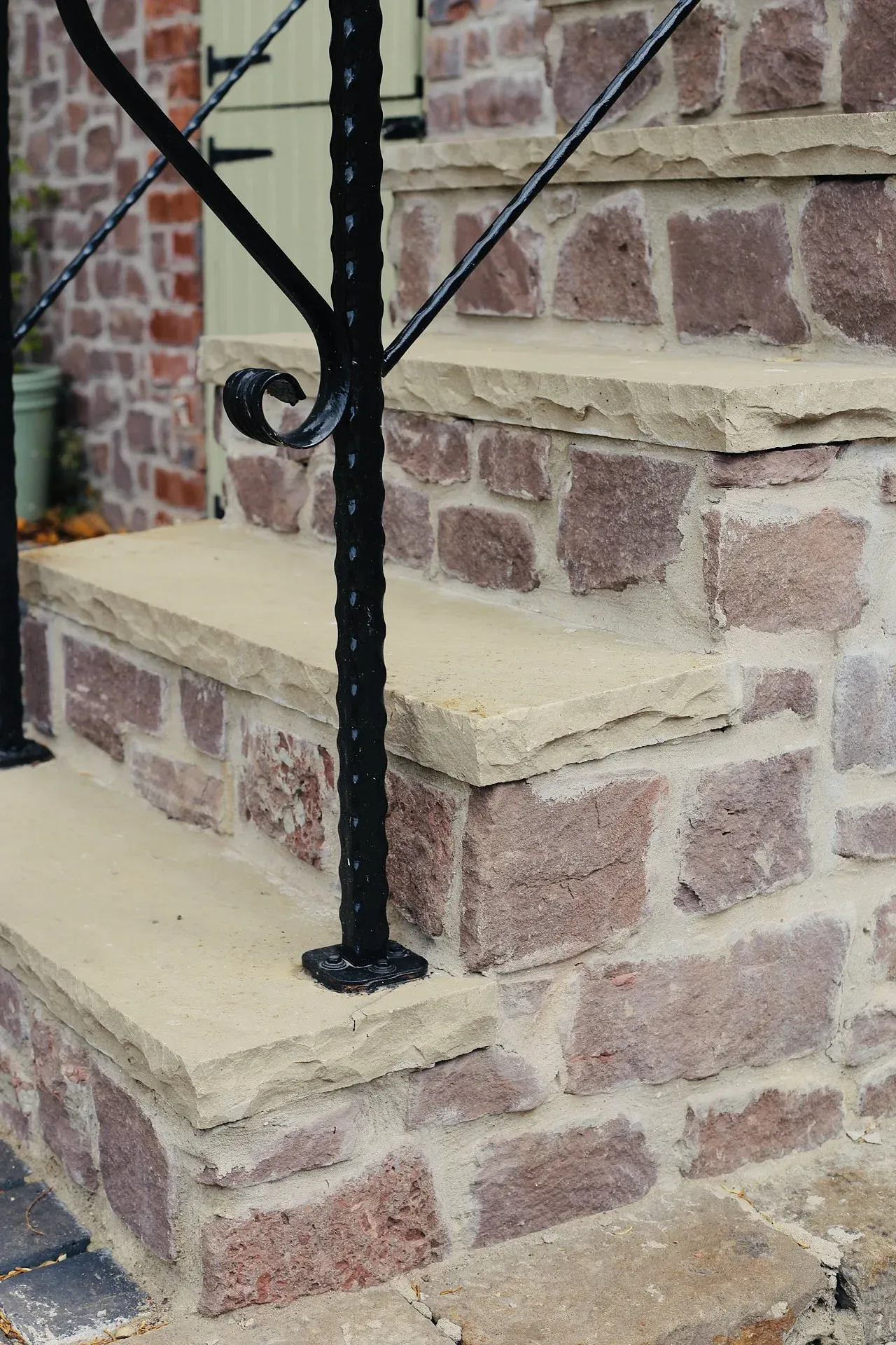 Detail of the stone steps and iron handrail against the red sandstone wall