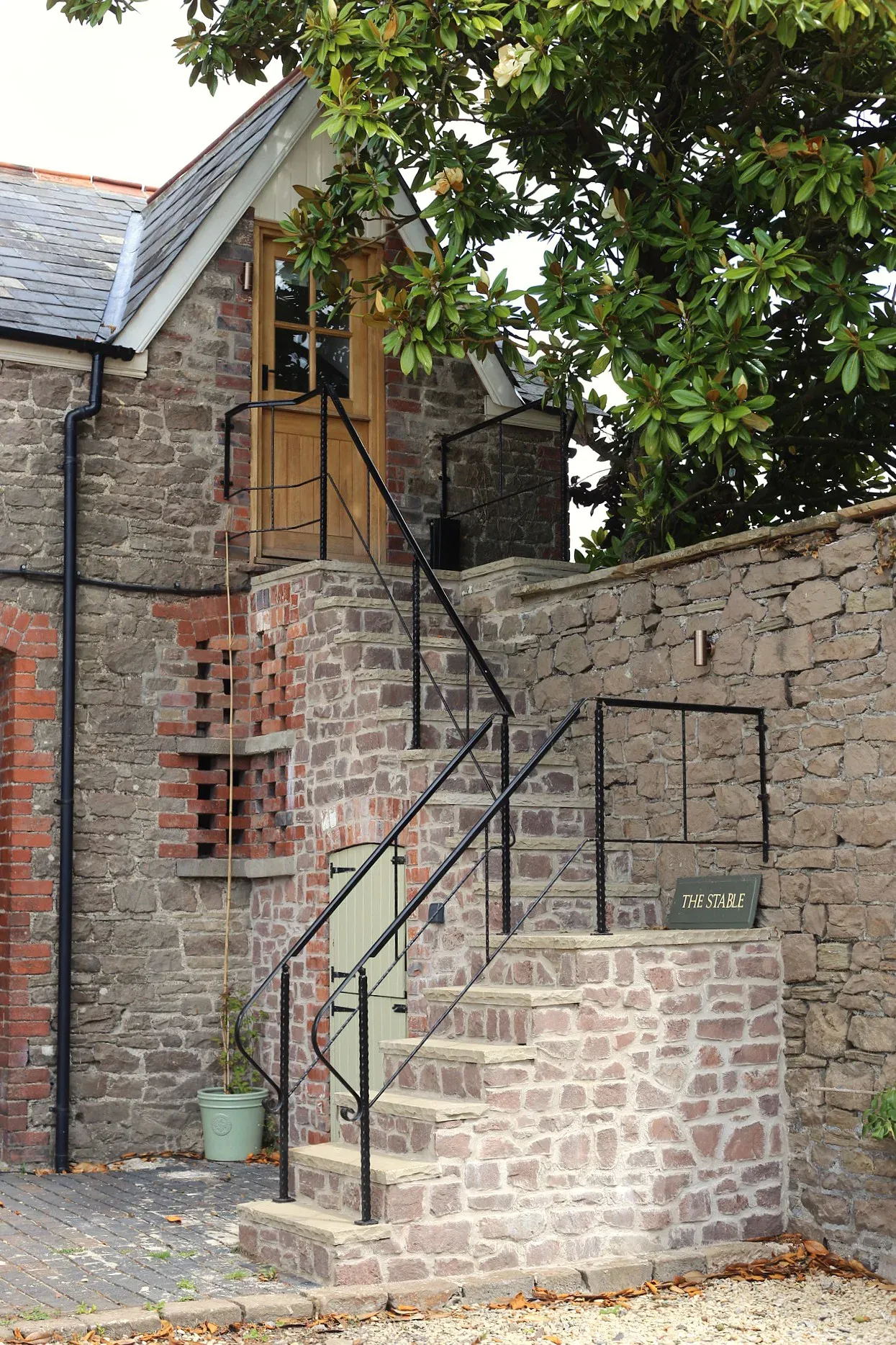 Stone steps with a wrought iron handrail leading up to the oak door of the converted stable