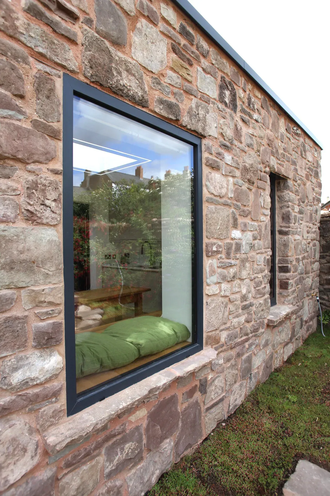 Picture window set into the stone wall, with a bench seat visible inside
