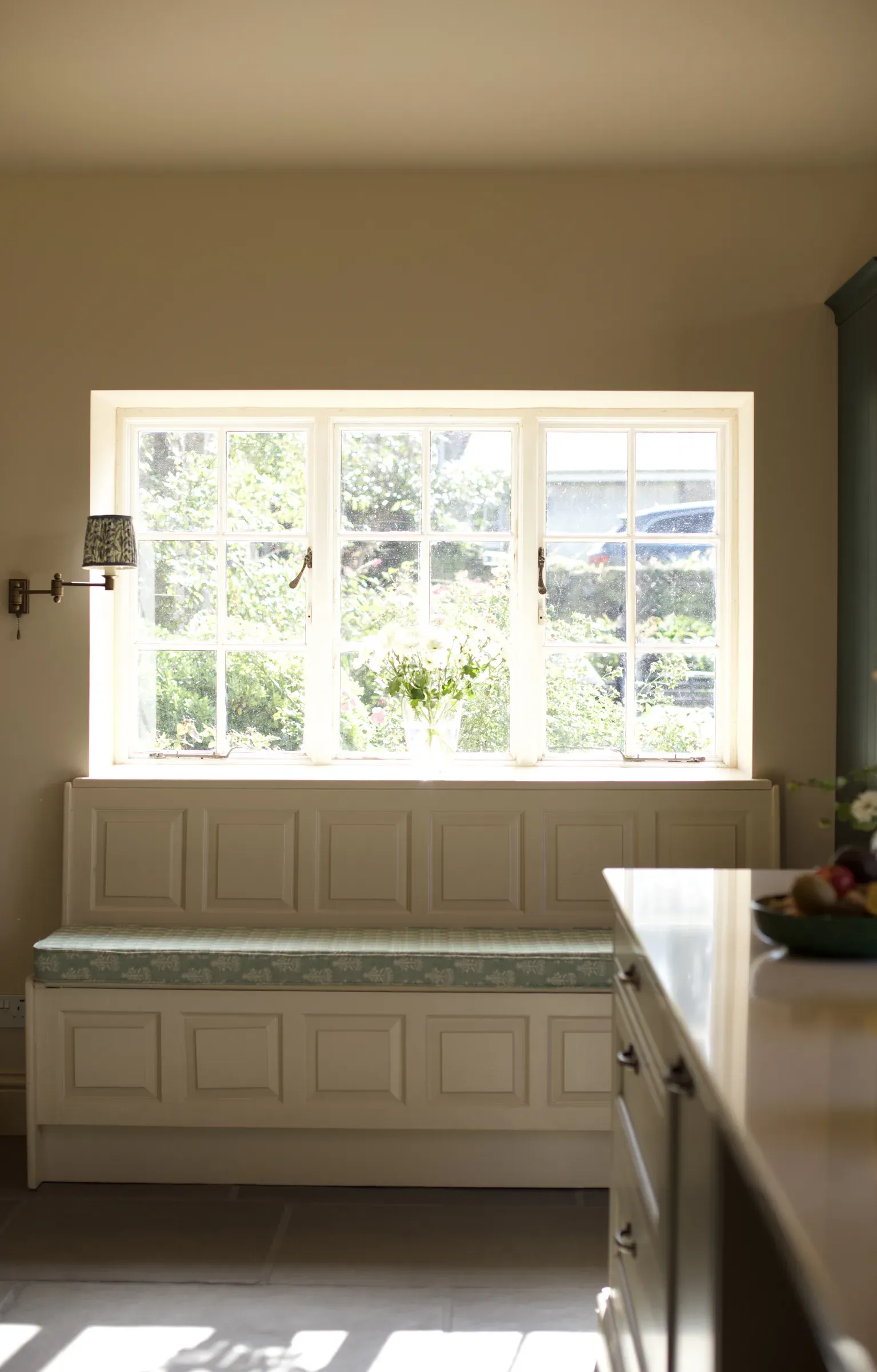 Built-in window seat with panelled front beneath a wide window
