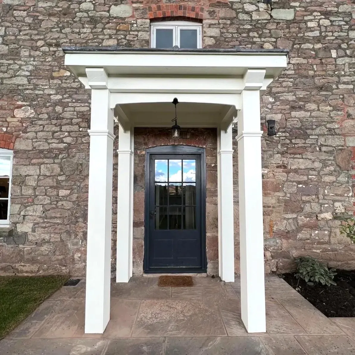 Close view of the portico and front door in the stone wall