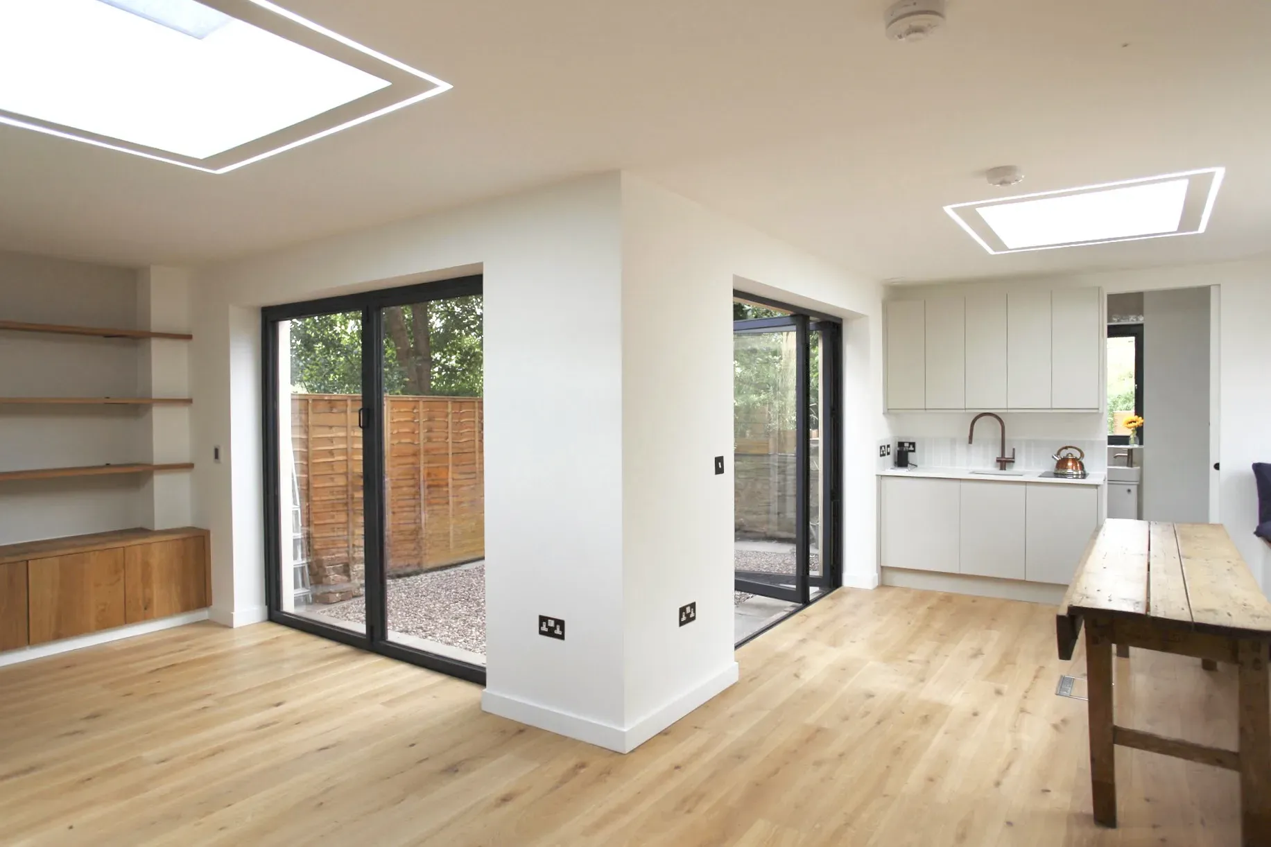 Interior with a rooflight, oak shelving, a kitchen and sliding doors to the courtyard