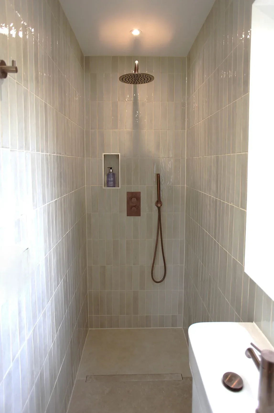 Shower room with pale vertical tiles and a rainfall shower