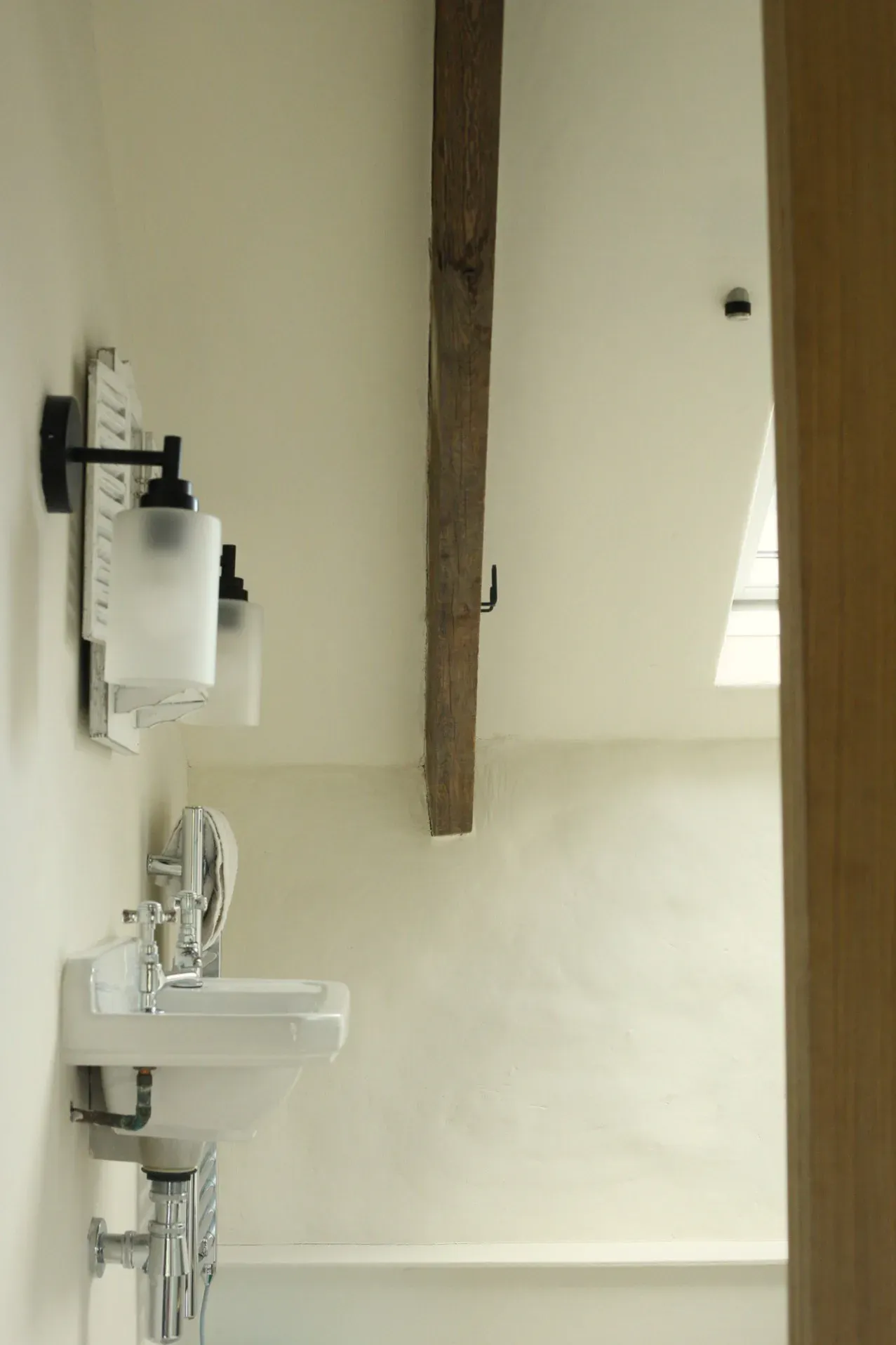 Bathroom with lime-plastered walls and an exposed oak beam